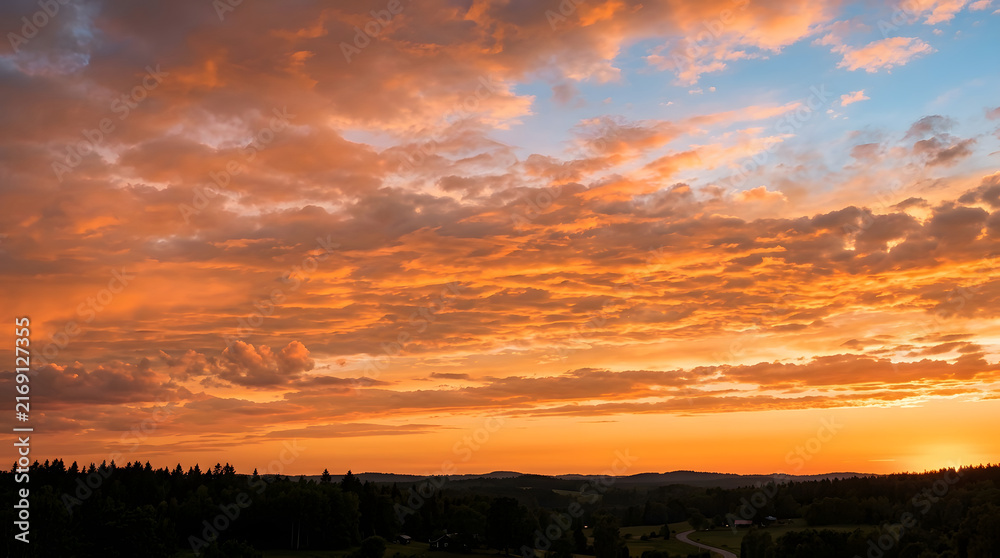 Obraz premium Vibrant Sunset Over Forested Hills with Dramatic Cloudscape