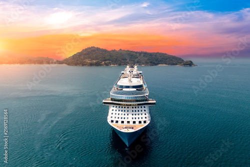 Aerial straight view typical cruise ship sailing on the ocean during a golden summer sunset with islands and mountains in the background.