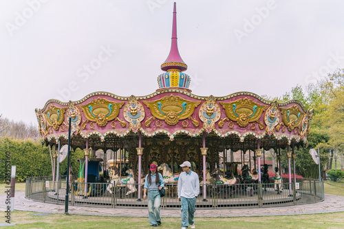 Photography Couple walking past a colorful carousel, Gucun Park, Shanghai