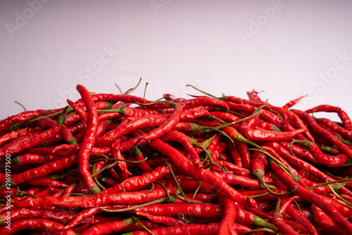 Obraz na plátně Wide angle studio photograph of a large mound of fresh red hot chilies set against a white background