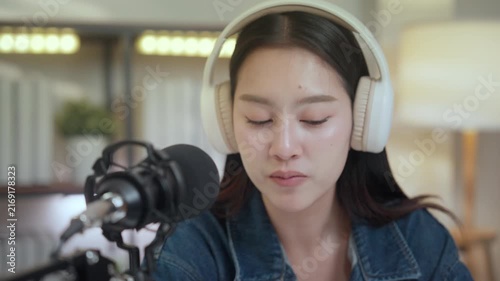 Podcast digital creator home studio microphone headphone female asian recording host shares stories with calm voice in cozy indoor setup, focused at desk with warm light for audio broadcast