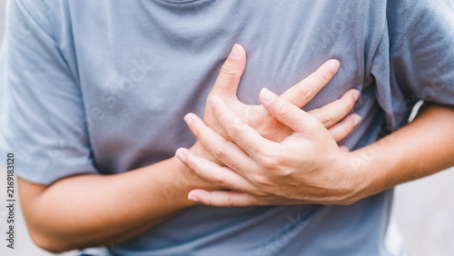 Quadro su tela Front view of a casual adult man clutching his chest outdoors in severe pain