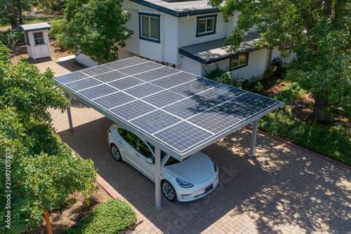 A white house, a solar panel covered carport and a white car parked beneath.