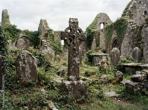 Ancient Celtic Cross in overgrown ruins of a historic Irish monastery.