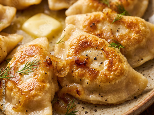 Golden pan fried Polish pierogi dumplings topped with caramelized onions butter and fresh dill