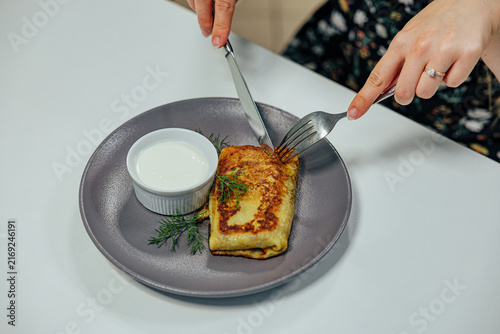 Konstfotografi Close overhead view of a diner cutting a golden stuffed pancake served with crea