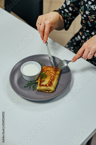 Konstfotografi Close overhead view of a diner cutting a golden stuffed pancake served with crea