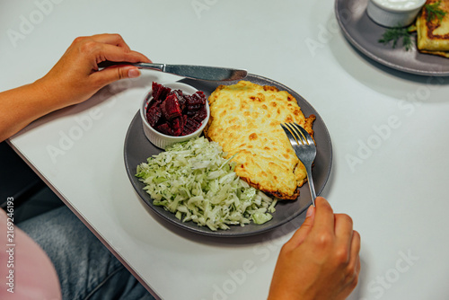 Konstfotografi Close overhead view of a diner holding cutlery beside a plate with golden baked