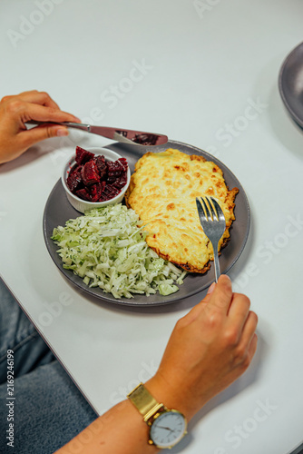 Canvas Print Close overhead view of a diner holding cutlery beside a plate with golden baked