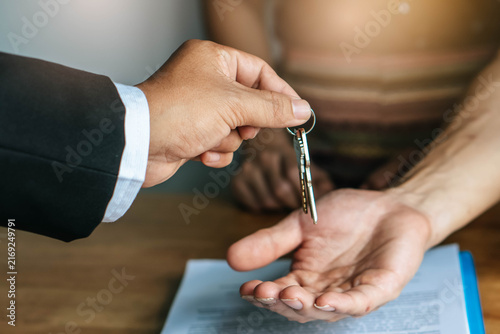 Photography close up view hand of property realtor giving key house to buyer / tenant