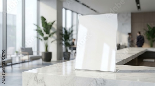 A blank vertical sign stand sits on a white marble counter in a bright modern office reception.