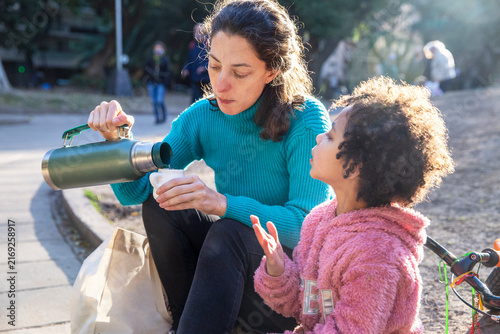 Multicultural mother and daughter preparing mate together outdoors in Argentina