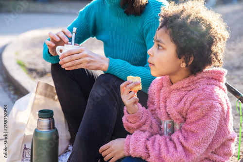 Mother and multiethnic daughter drinking mate in park