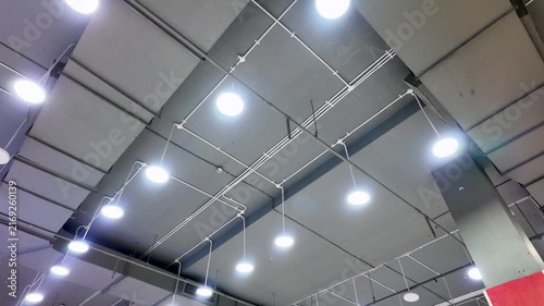 Modern industrial ceiling interior with hanging round LED lights and metal structures.
