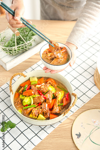 Roasted Duck Stew with Vegetables Being Served from Casserole Dish in Farmhouse Kitchen