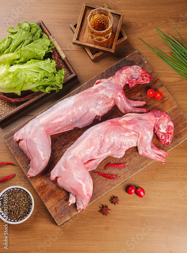 Fresh Whole Free-Range Rabbit Meat on Rustic Wooden Board with Vegetables and Spices for Traditional Farmhouse Mountain Cooking