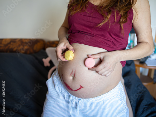 Bild auf Leinwand Creative Pregnancy Concept with Macaron Eyes on Smiling Baby Bump