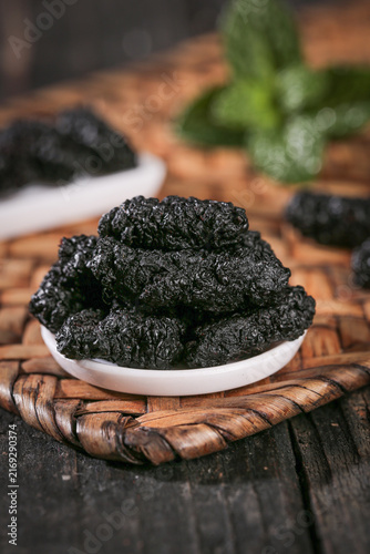 Fotografie Black Mulberry Tea Leaves from Xinjiang China Closeup Display on Bamboo Mat