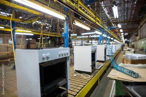 White ovens on factory assembly line under industrial lighting