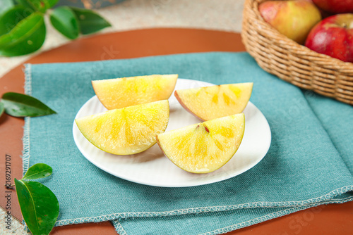 Foto Fresh Yellow Apple Slices on Plate with Fruit Basket - Healthy Snack Food Photog