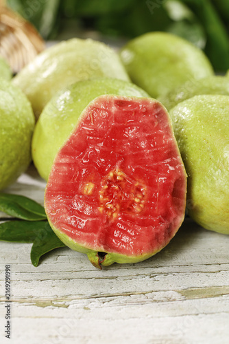 Fotografie Fresh Red Guava Fruit Cut Open on Wooden Base Showing Carmine Flesh and Seeds