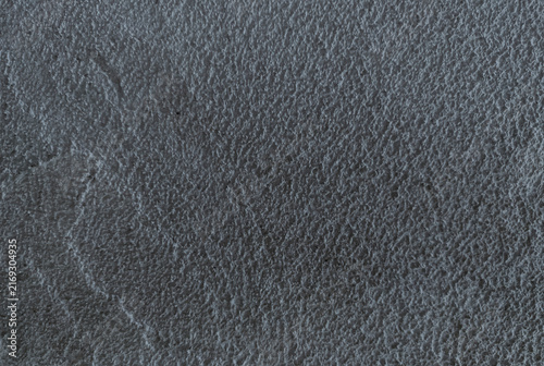 Detailed close-up of rough grunge wall background texture gray asphalt material with fine scattered stones.