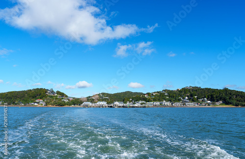 Water trails behind ferry leaving Paihia waterfront.