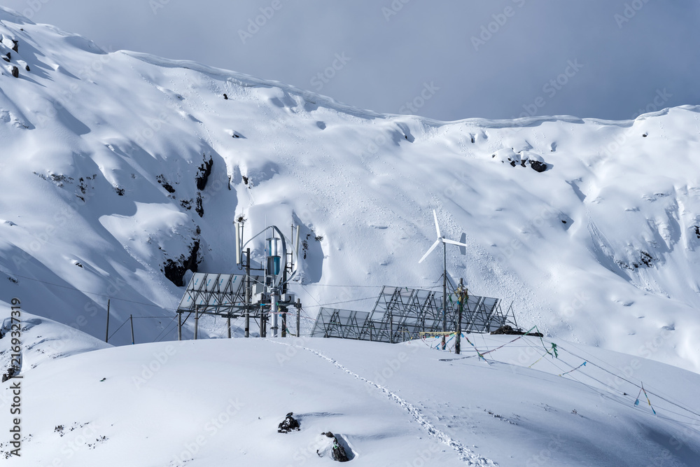 Fototapeta premium Solar panels and wind turbine on a snowy mountain pass
