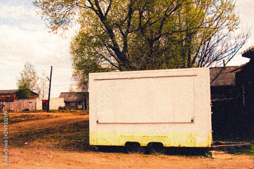Cinematic vintage illustration of an abandoned white commercial trailer in rural village