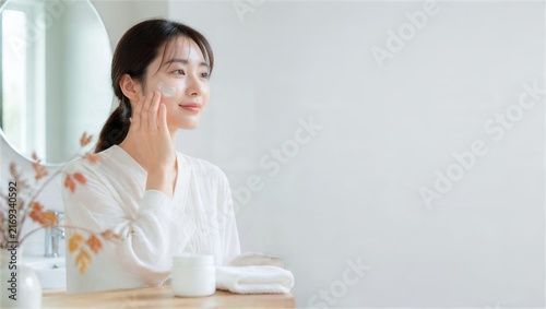 秋の洗面所で保湿剤を頬になじませる女性
