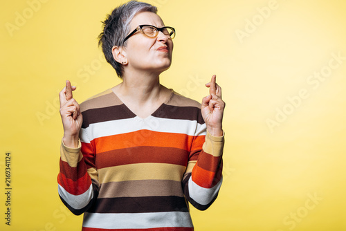 Woman closing eyes and crossing fingers on both hands, wishing for good fortune and hoping for success