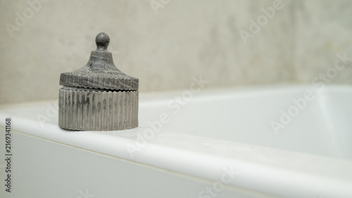 Фотография Elegant grey decorative container on white bathtub edge in minimalist bathroom