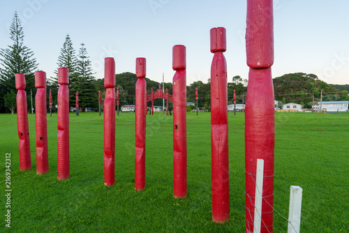 Carved red pou (posts) standing in a grassy field Located near Waitangi and Paihia in the Bay of Islands