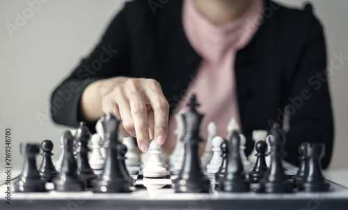 Fotografie Hand of businesswoman moving white king chess piece on chessboard for business s