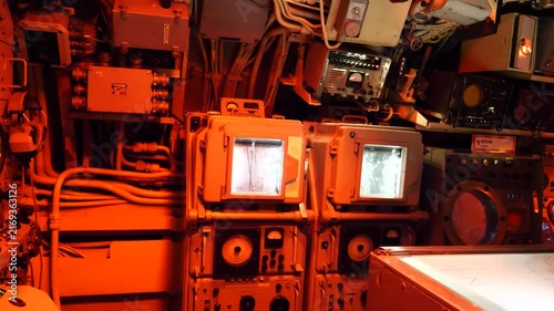 Vintage submarine control room with red lighting and analog radar screens.