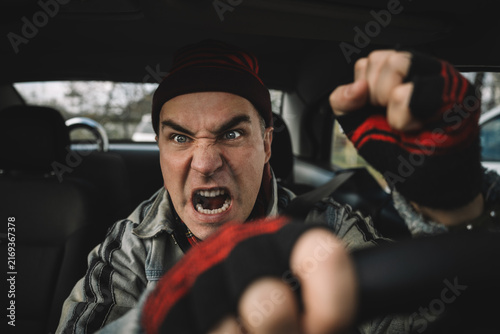 Foto Aggressive man shouting while driving a car, expressing road rage, anger and dangerous emotional behavior behind the wheel during urban traffic