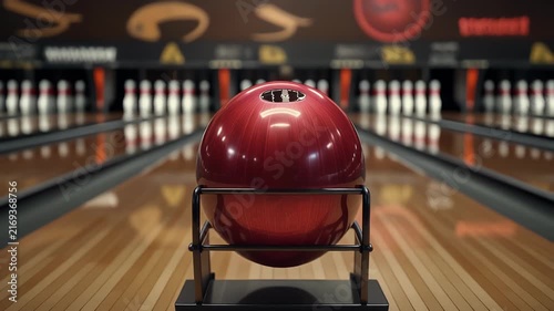 Close-up of a red bowling ball on a rack at the start of a lane.