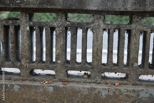 Weathered concrete bridge railing with textured stone pillars and vintage architectural design