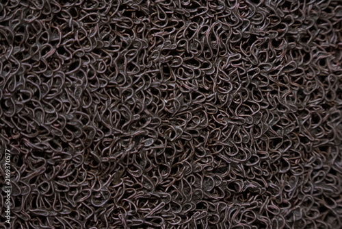 Dark brown textured noodle mat surface, close up of synthetic rubber floor covering pattern.