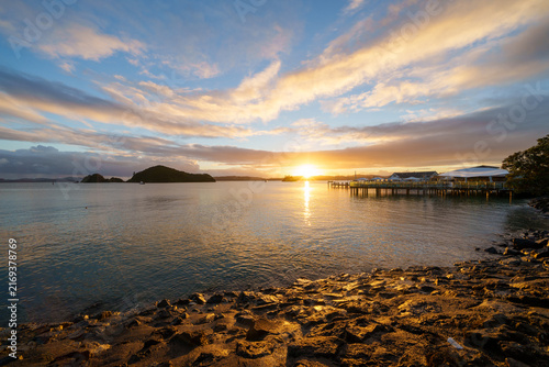 Paihia waterfront at sunrise with suns golden glow on distant horizon