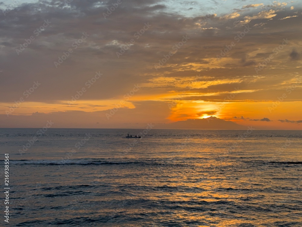 Obraz premium Golden sunset over ocean with small fishing boat silhouette