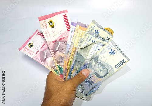 Fotografía Hand fans out colorful local currency bills against a white background