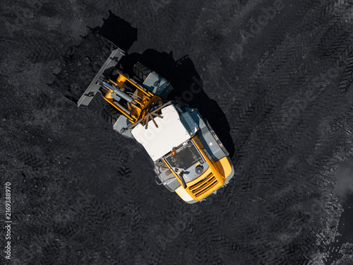 Obraz na płótnie Yellow loader operating on coal pile in mining open pit aerial view