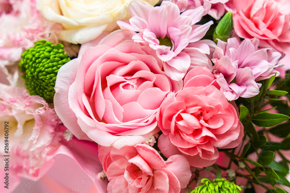 Fototapeta premium Colorful carnation flowers arranged in a bouquet with various types and shapes placed on a light surface