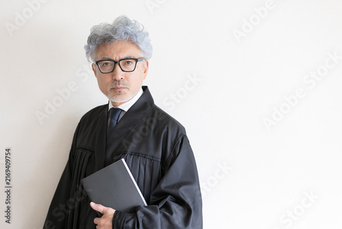 Foto 法律書を手にカメラを見つめる法服姿の男性裁判官