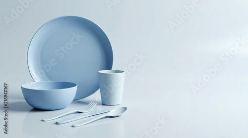 Biodegradable tableware set with plate, bowl, cup and cutlery on a clean white background.