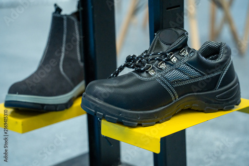 Принти на полотні Two pairs of sturdy work boots displayed on yellow shelves