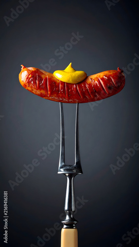 Grilled Sausage on Fork with Mustard Pouring on Top
