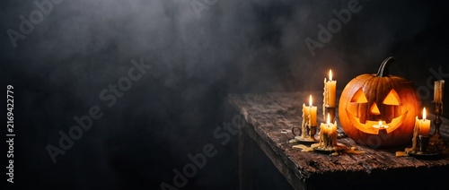 Spooky carved pumpkin with glowing eyes and burning candles on rustic wooden table at night perfect for halloween celebrations
