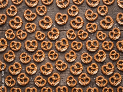Salty pretzels pattern on rustic dark wooden background for food background texture